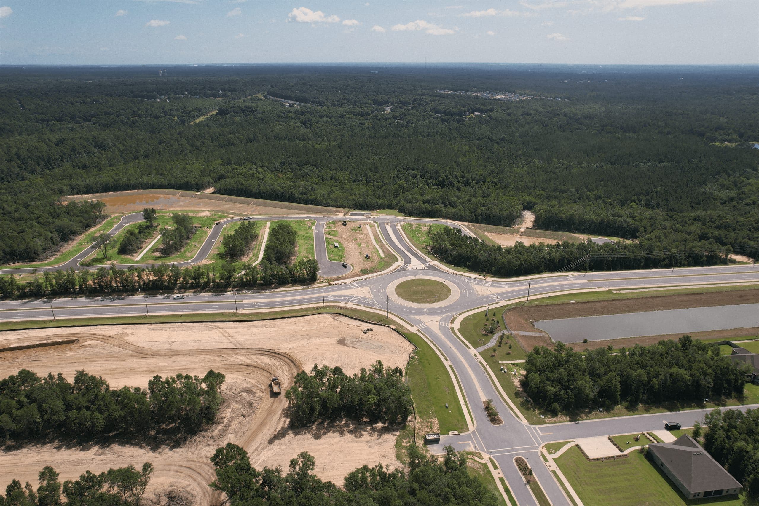 Aerial view of a residential development with finished streets, curbs, and a new roundabout