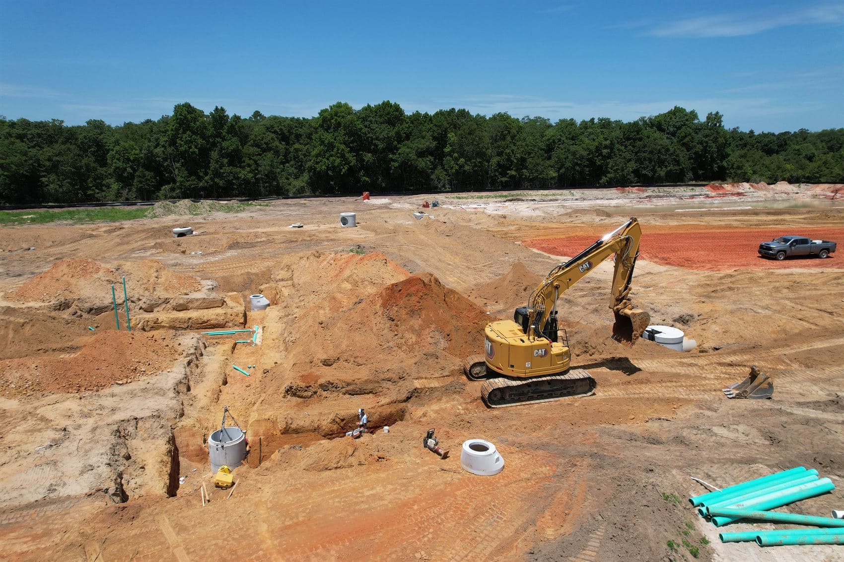 Excavator setting storm drainage structures during subdivision infrastructure construction