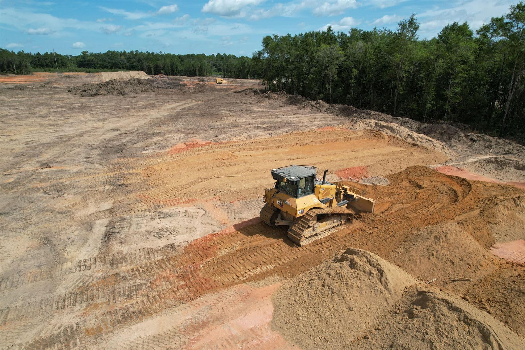 Aerial view of a dozer shaping graded earth on a cleared development site